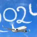 white plane flying in the sky with clouds shaped like "2024"